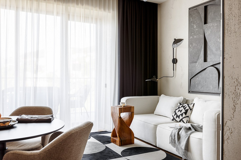 Minimalizm i biel Przestronna biała sofa z miękkimi poduszkami w minimalistycznym wnętrzu pokoju.