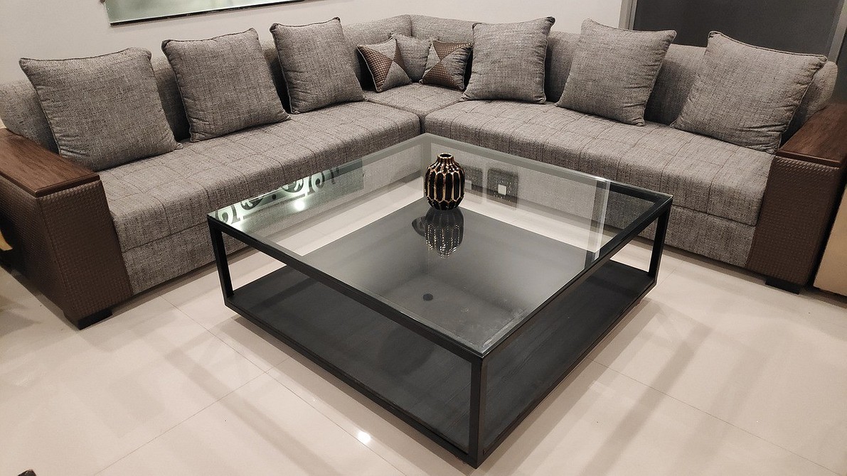 Ciemna sofa z poduszkami o różnych fakturach i kolorach - aranżacja salonu 2026.