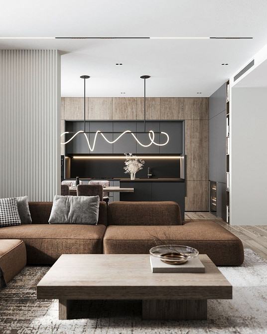 Okno na świat Brązowa kanapa z poduszkami różnych odcieni w salonie z dużym oknem.