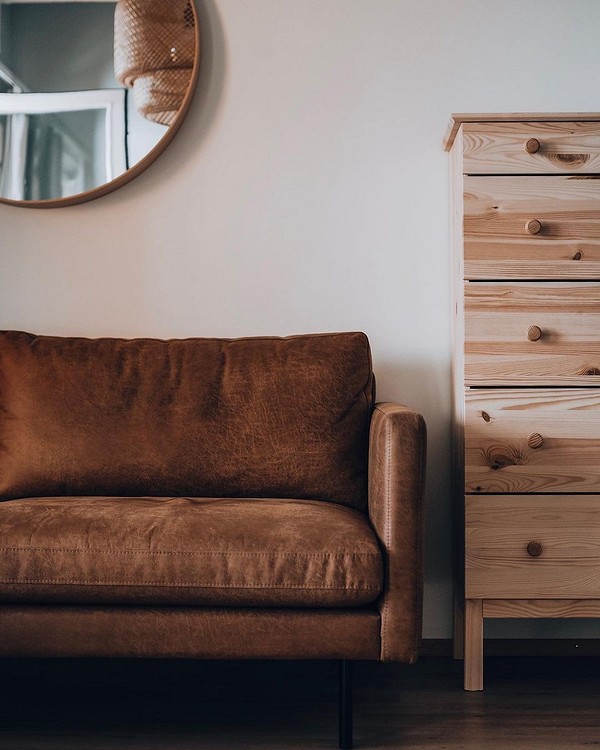 Skandynawski klimat Brązowa sofa w stylu skandynawskim z drewnianymi nóżkami i pledem. Naturalny design.