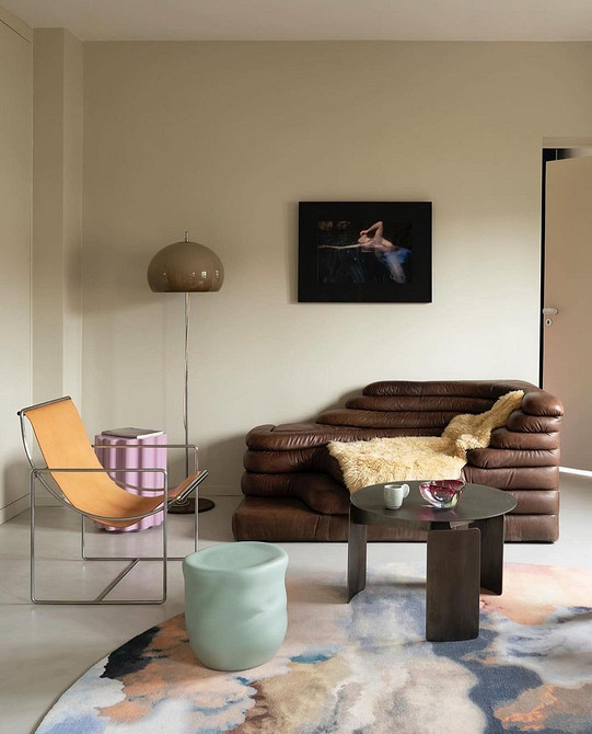 Poduszki i zieleń Brązowa sofa z poduszkami różnych odcieni w salonie z roślinami. Naturalne kolory.