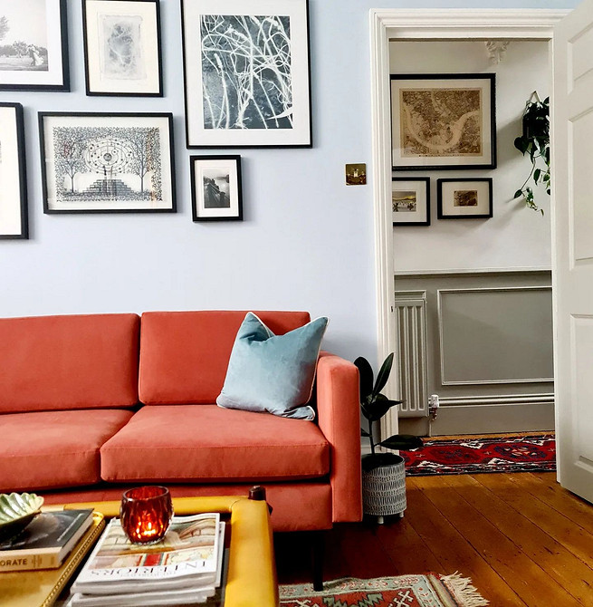 Wnętrze salonu: połączenie czerwonej sofy, szarych ścian i drewnianego stolika.