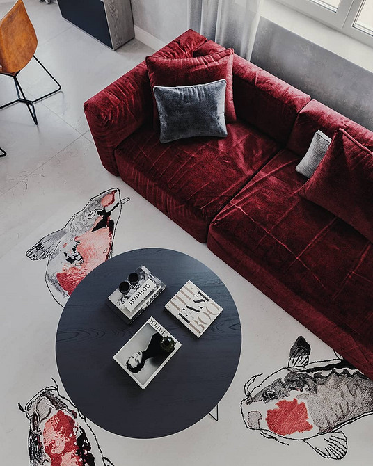 Narożna czerwona sofa i stolik kawowy w przestronnym salonie. Nowoczesna aranżacja.