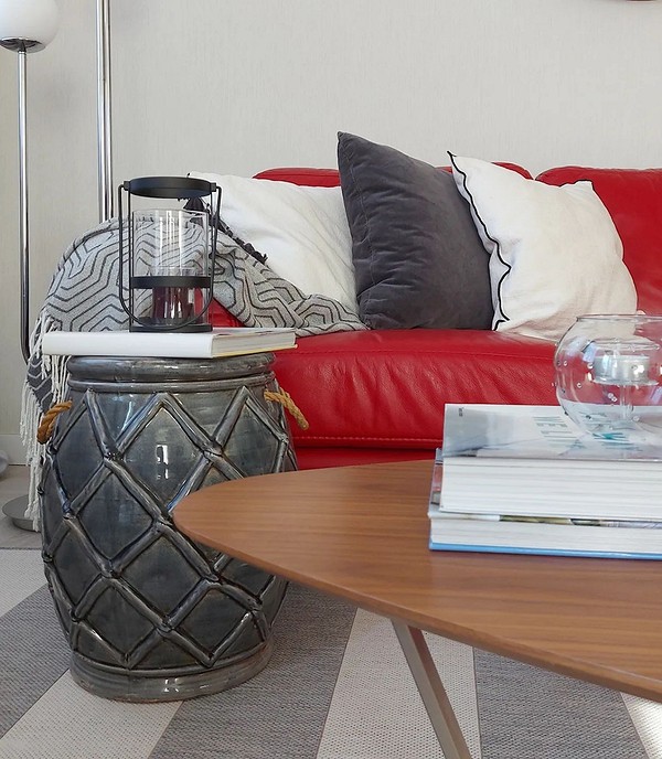 Mała czerwona sofa w minimalistycznym salonie z szarymi ścianami. Nowoczesny styl.