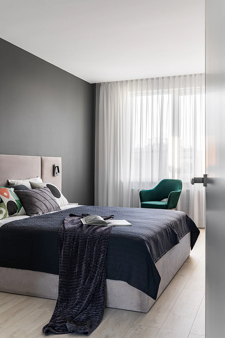 Szarość i drewno Sypialnia w szarościach z miękkim szarym łóżkiem i drewnianymi elementami dekoracyjnymi.