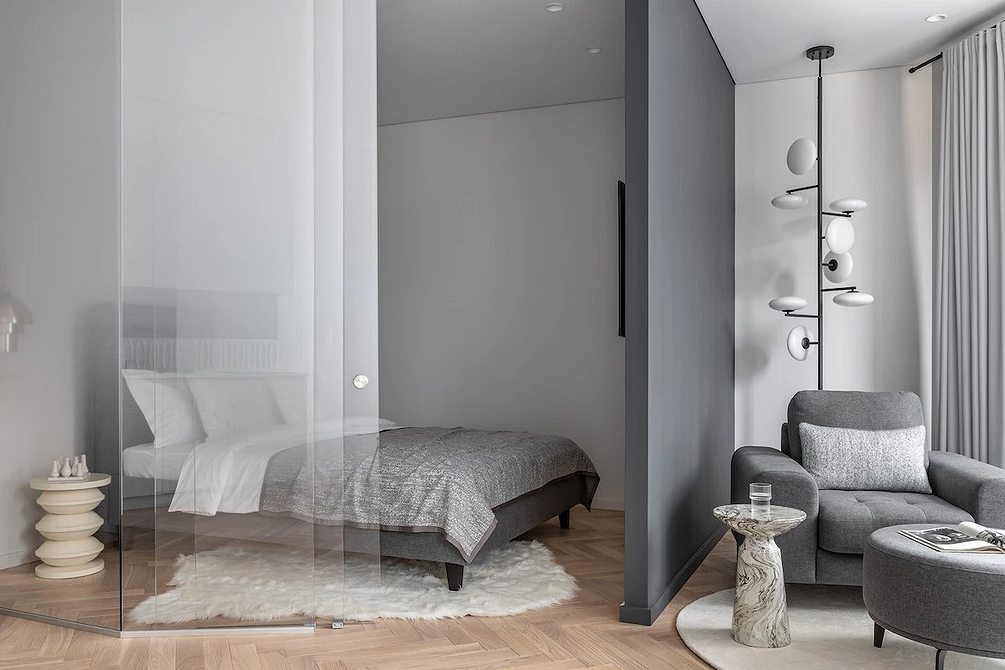 Minimalizm w szarości Nowoczesna sypialnia z szarym łóżkiem i minimalistycznym dekorem na ścianie.