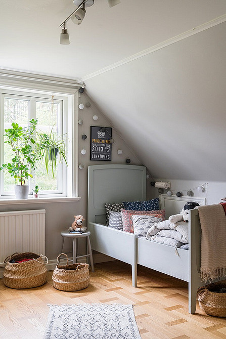 Komfortowe szare łóżko Szare łóżko z miękkim zagłówkiem w nowoczesnej sypialni z drewnianymi meblami.