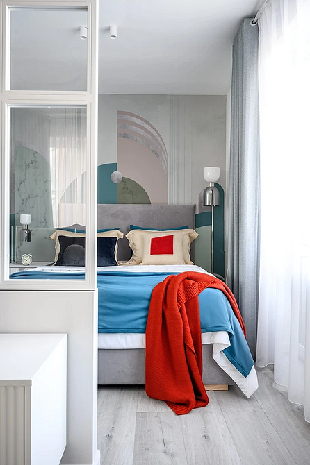 Ciepła szara sypialnia Przytulna sypialnia z szarym łóżkiem, dekoracyjnymi poduszkami i ciepłym oświetleniem.