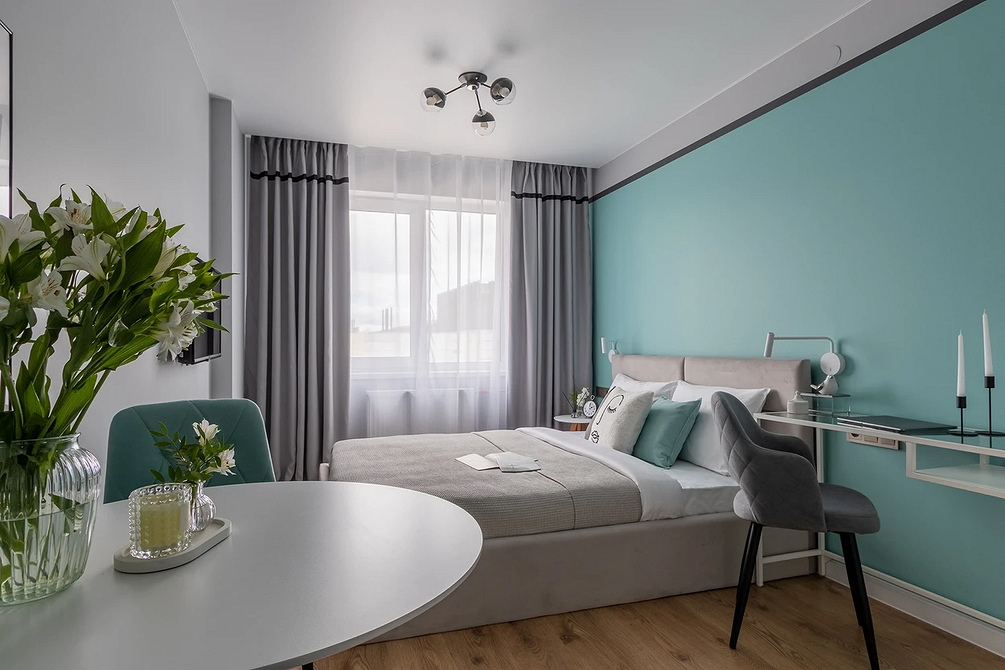 Sztuka i szarość Stylowa sypialnia z szarym łóżkiem, ozdobiona roślinami i elementami artystycznymi.