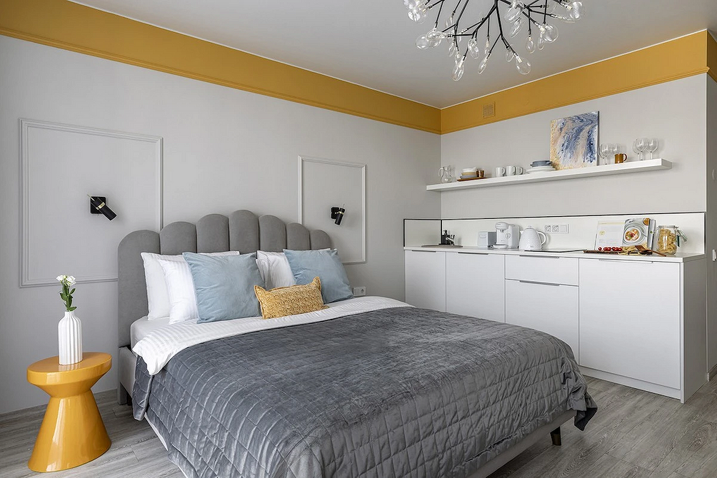 Szarość i drewno Sypialnia z szarym łóżkiem, drewnianymi szafkami nocnymi i stylową lampą.