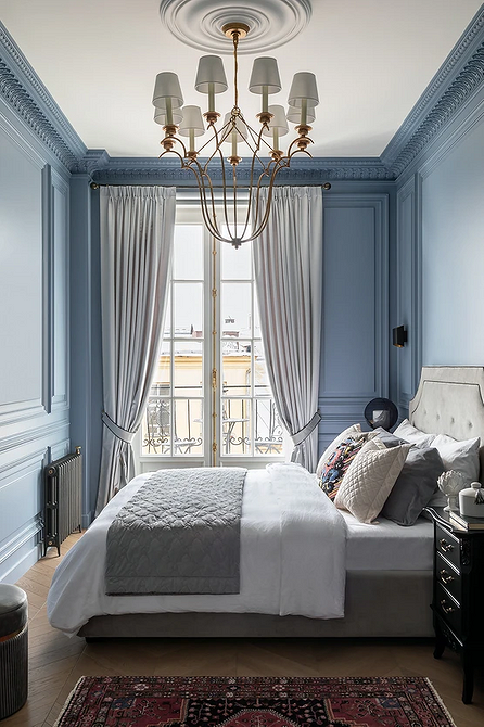 Minimalizm i szarość Nowoczesna sypialnia z szarym łóżkiem, minimalizmem i dużym oknem w pokoju.