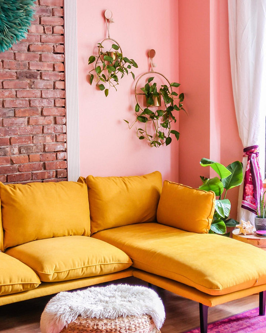 Żółta sofa: Welur Żółta welurowa sofa w pokoju z półkami na książki i lampą podłogową